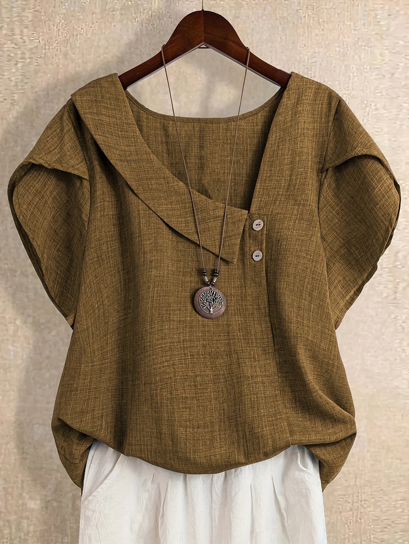 Plus-size women's asymmetrical solid color T-shirt with unique button detail, featuring a comfortable loose fit, suitable for ca