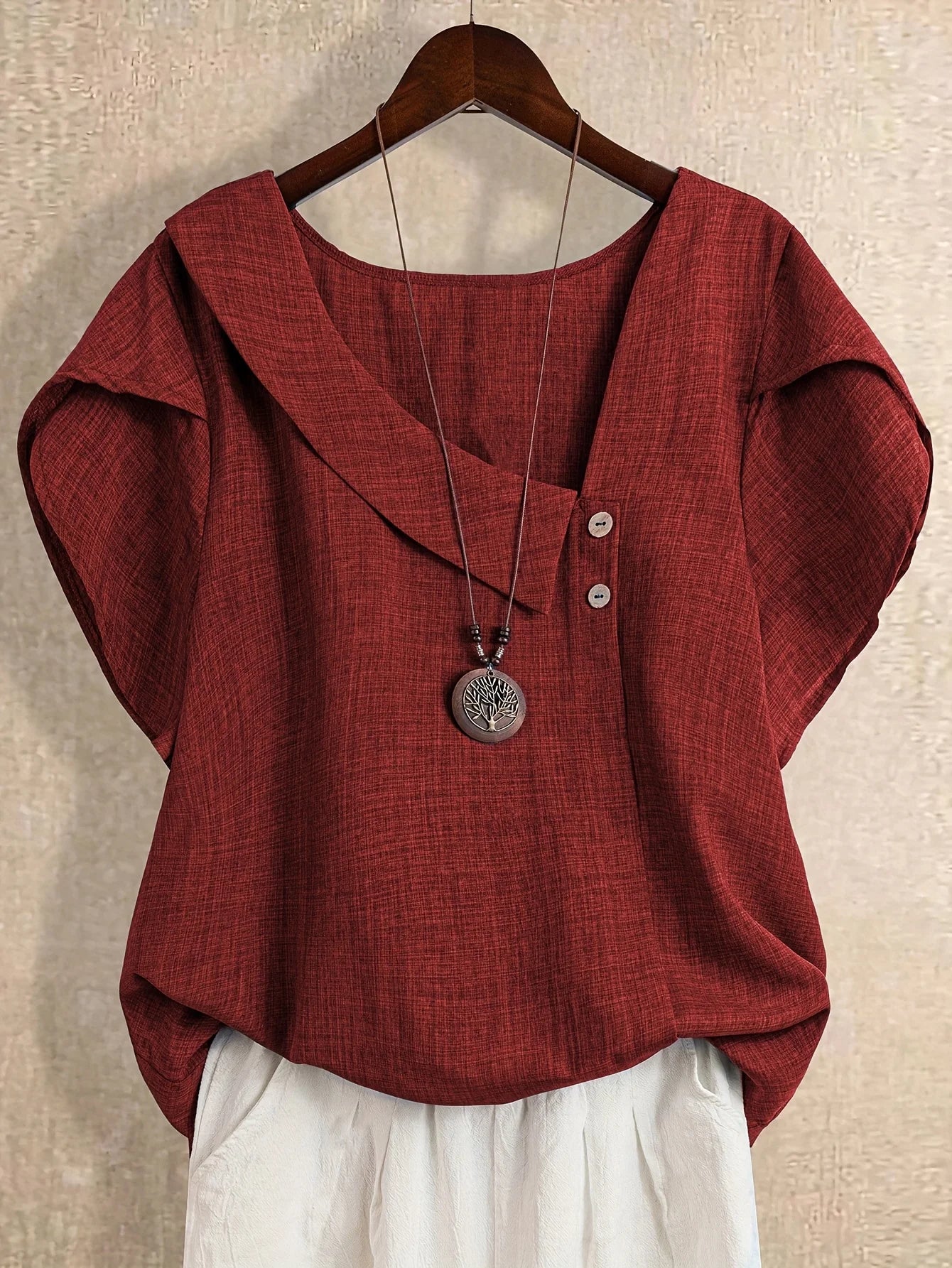 Plus-size women's asymmetrical solid color T-shirt with unique button detail, featuring a comfortable loose fit, suitable for ca