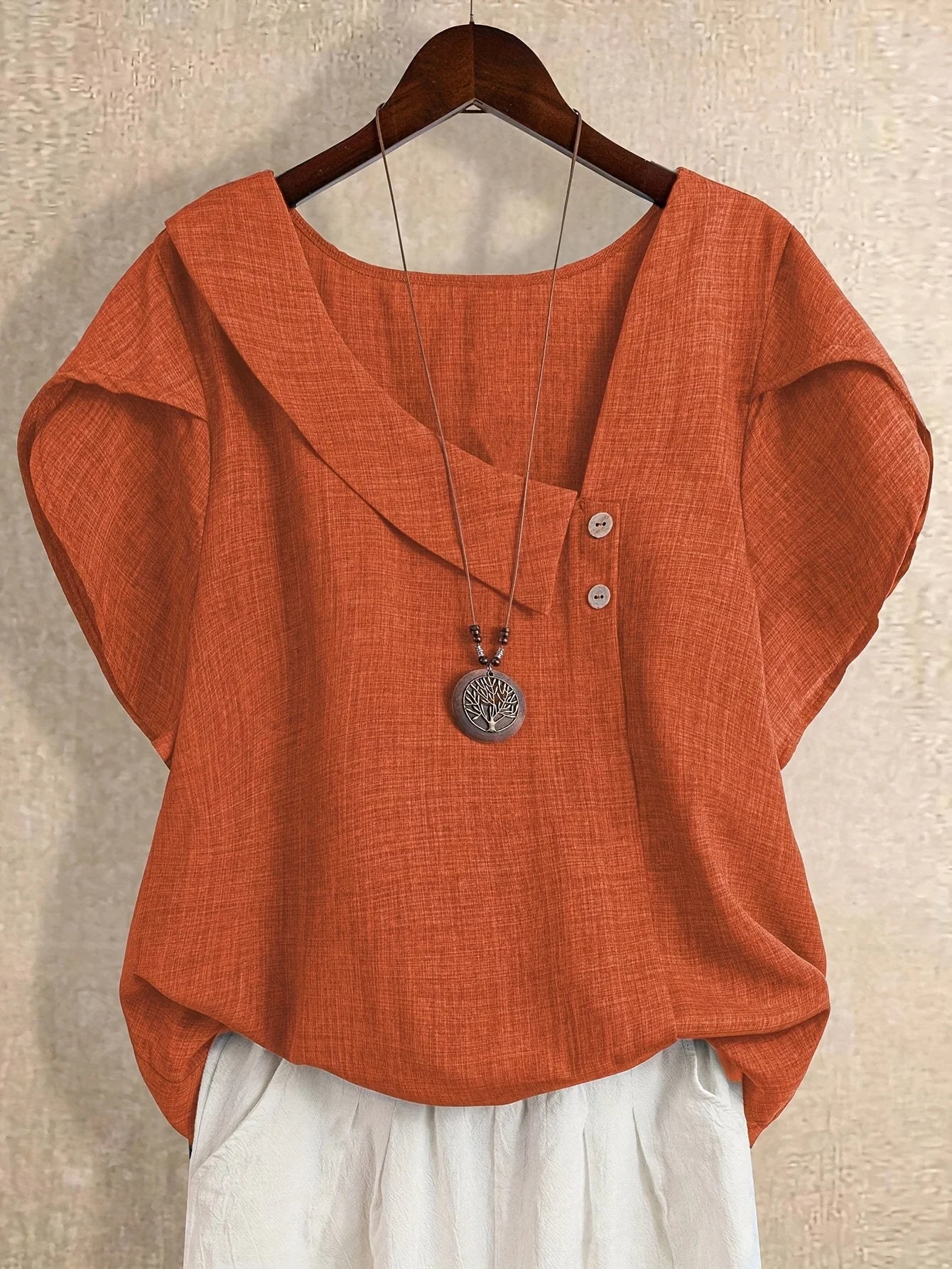 Plus-size women's asymmetrical solid color T-shirt with unique button detail, featuring a comfortable loose fit, suitable for ca