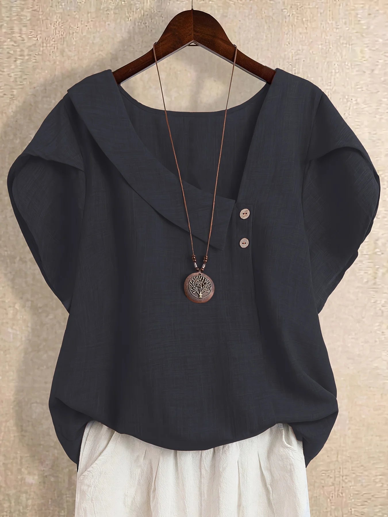 Plus-size women's asymmetrical solid color T-shirt with unique button detail, featuring a comfortable loose fit, suitable for ca