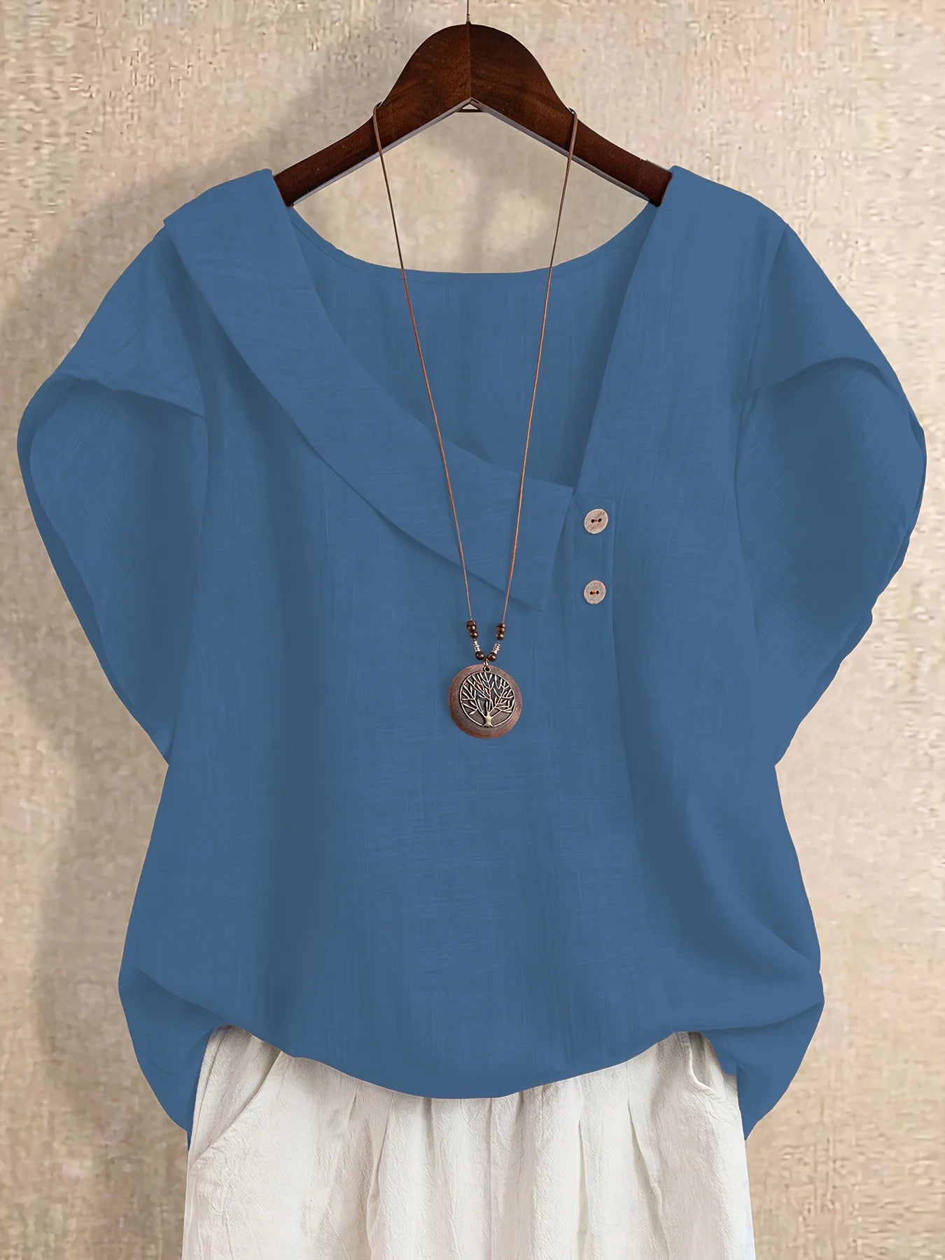 Plus-size women's asymmetrical solid color T-shirt with unique button detail, featuring a comfortable loose fit, suitable for ca